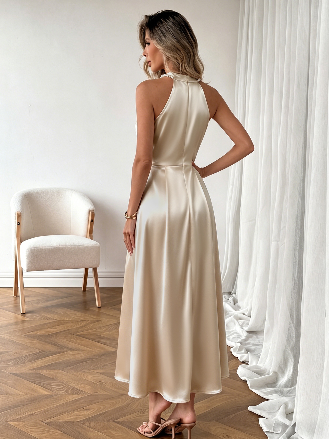Vestido largo de satén color champán con escote halter y perlas en el cuello.