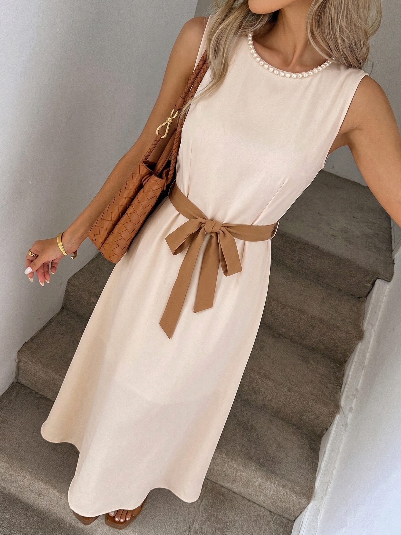 Abito midi beige senza maniche con cintura e rifiniture in perle.