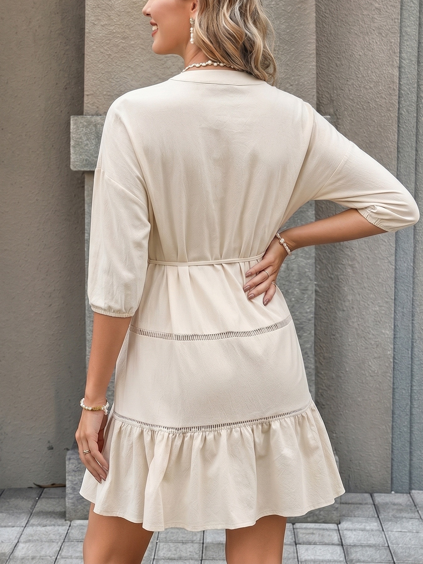 Mini abito beige con bottoni sul davanti e orlo a balze.