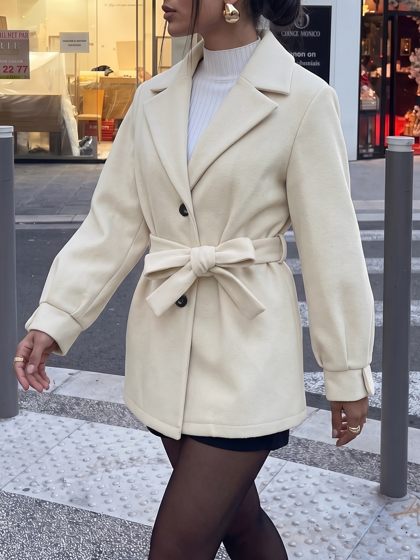 Cappotto beige con cintura e abbottonatura frontale, con colletto a revers.