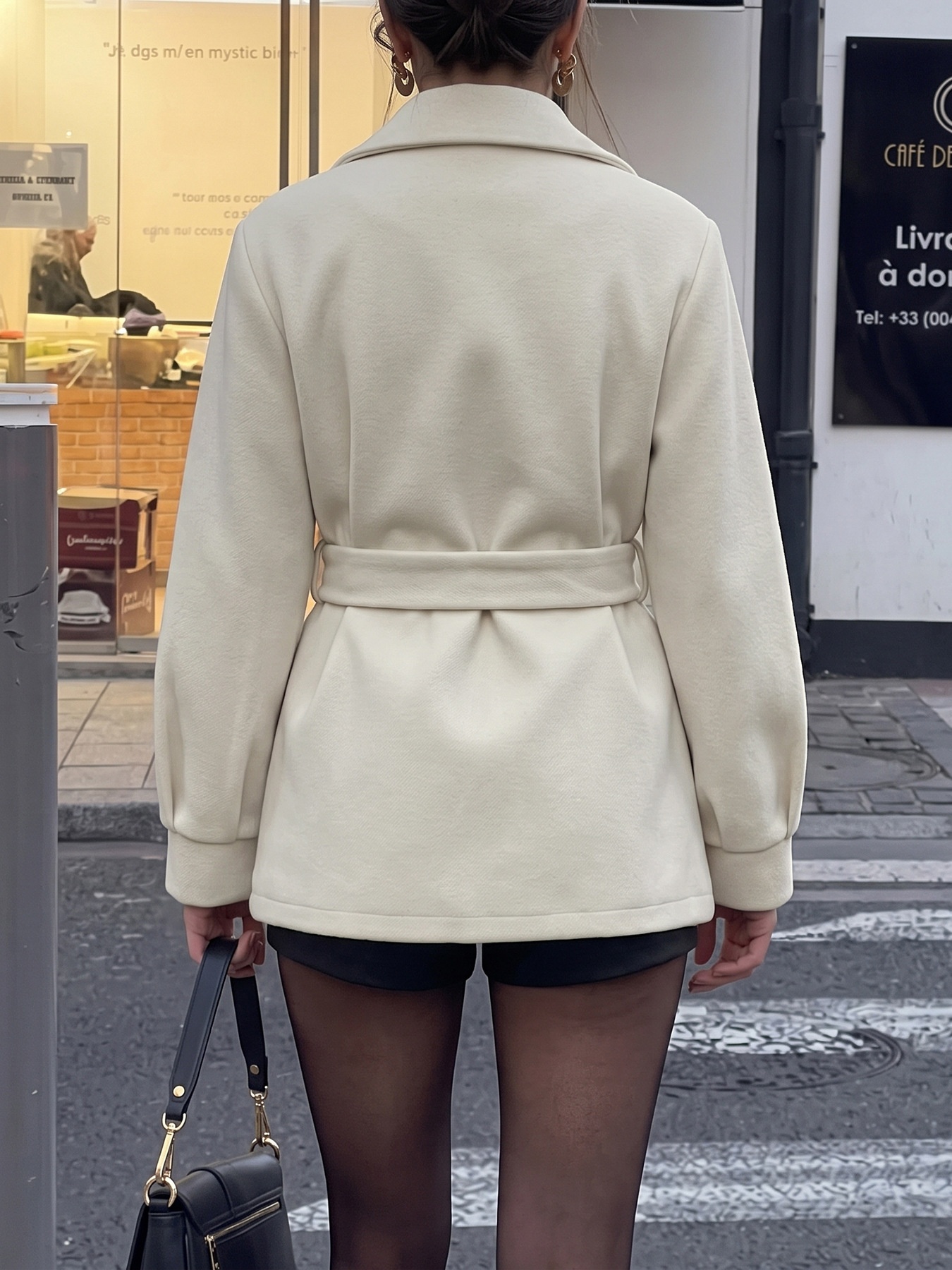 Cappotto beige con cintura e abbottonatura frontale, con colletto a revers.