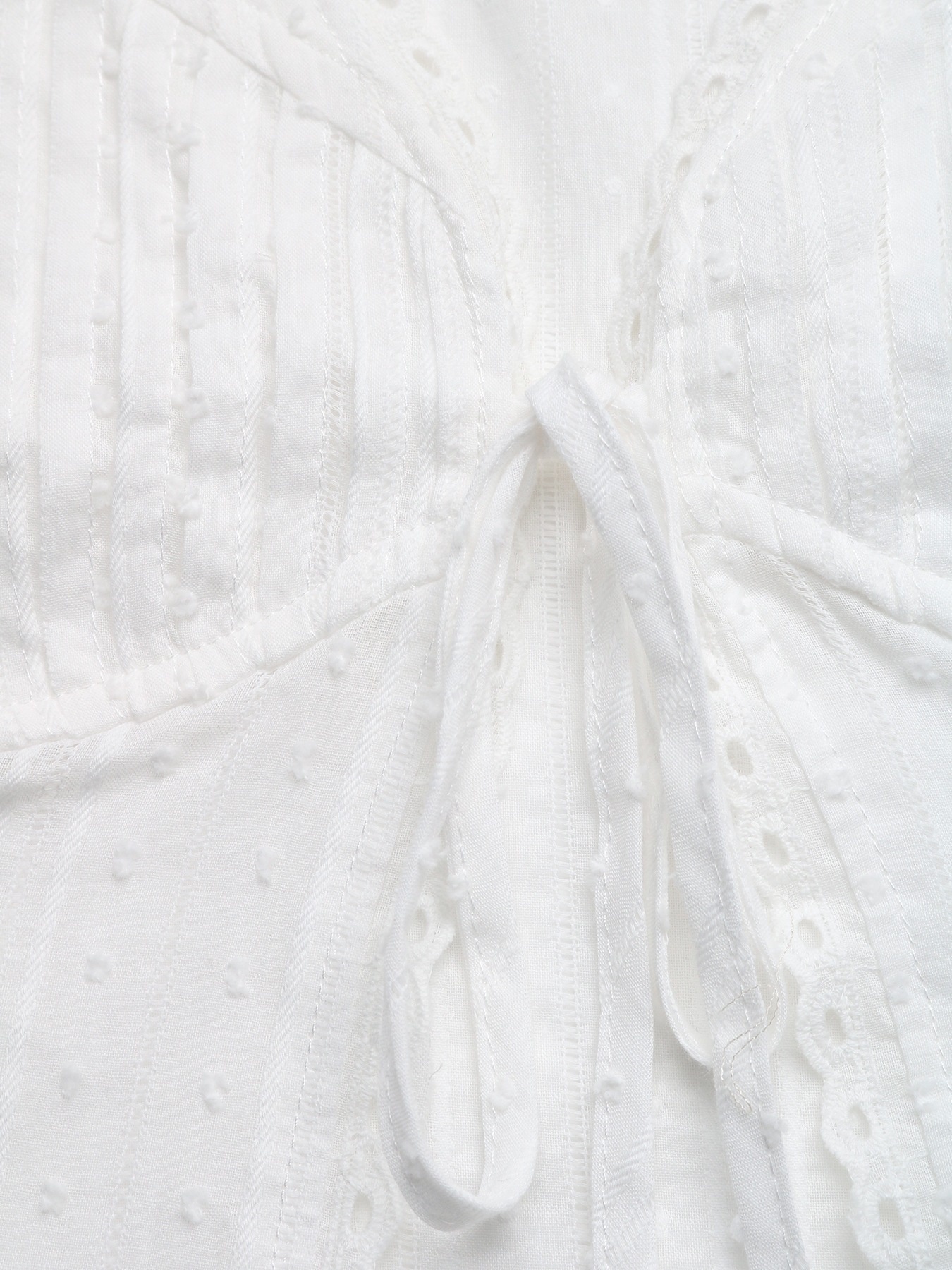 Top bianco senza maniche con scollo a V e allacciatura sul davanti, con bordo in pizzo.