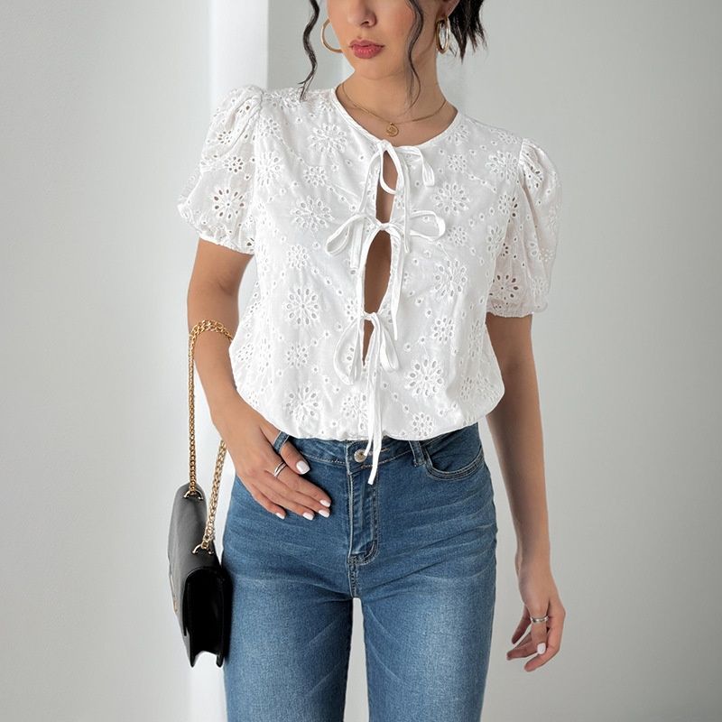 Top blanco con mangas abullonadas y detalle de ojales y lazo frontal.