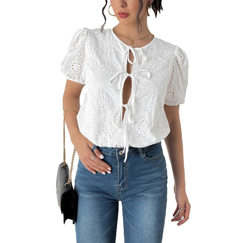 Top blanco con mangas abullonadas y detalle de ojales y lazo frontal.