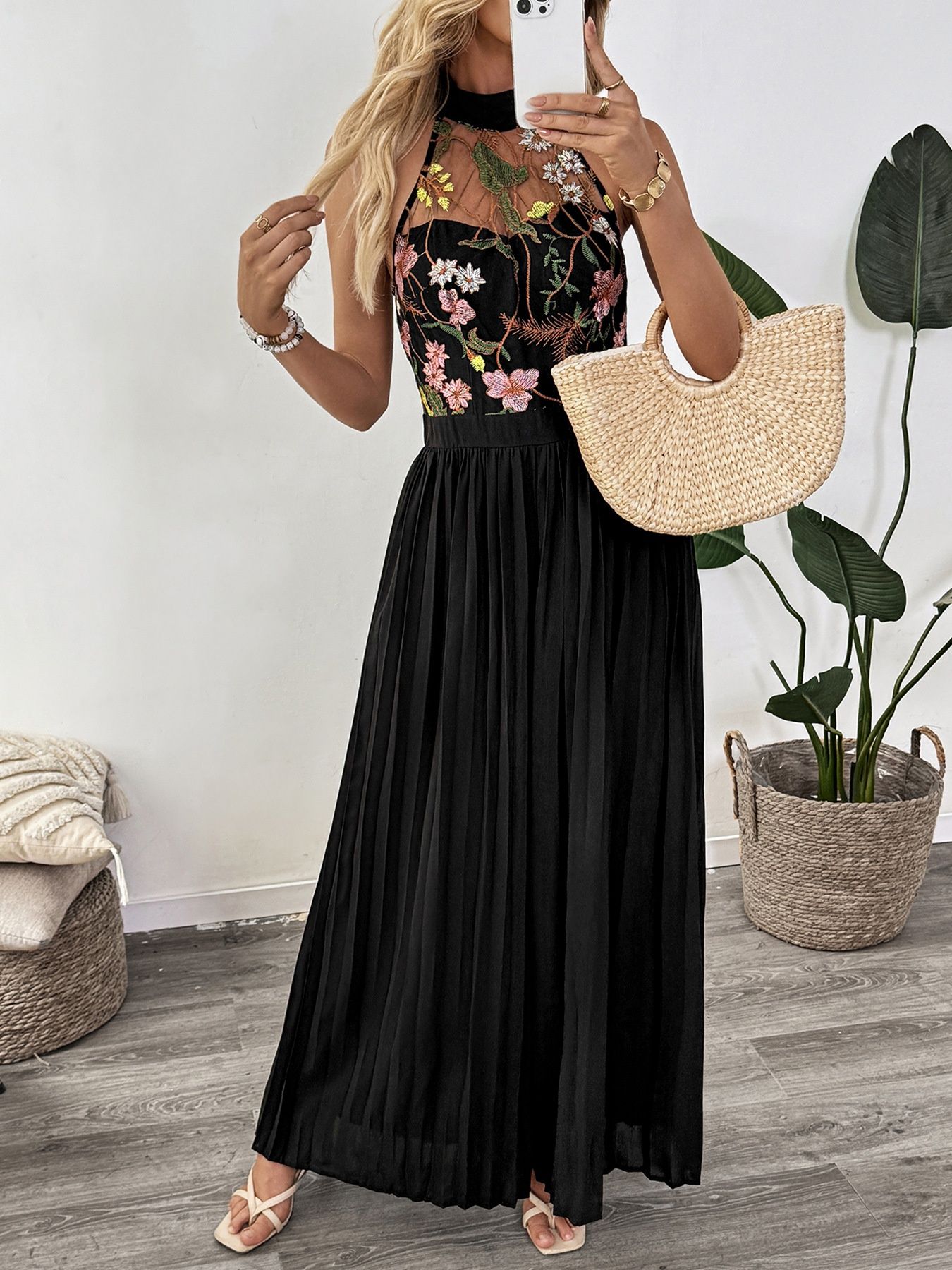 Mono negro con estampado floral, escote halter y pernera ancha plisada.