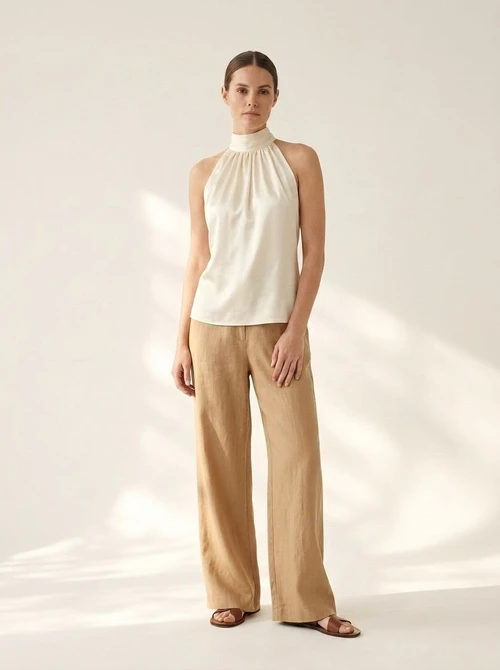 Haut court élégant en satin blanc cassé à col halter et dos nu.
