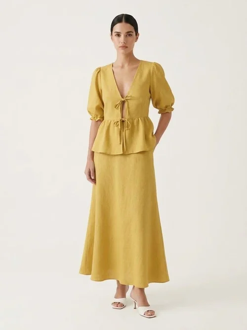 Completo giallo composto da top peplum con maniche a sbuffo e gonna lunga.