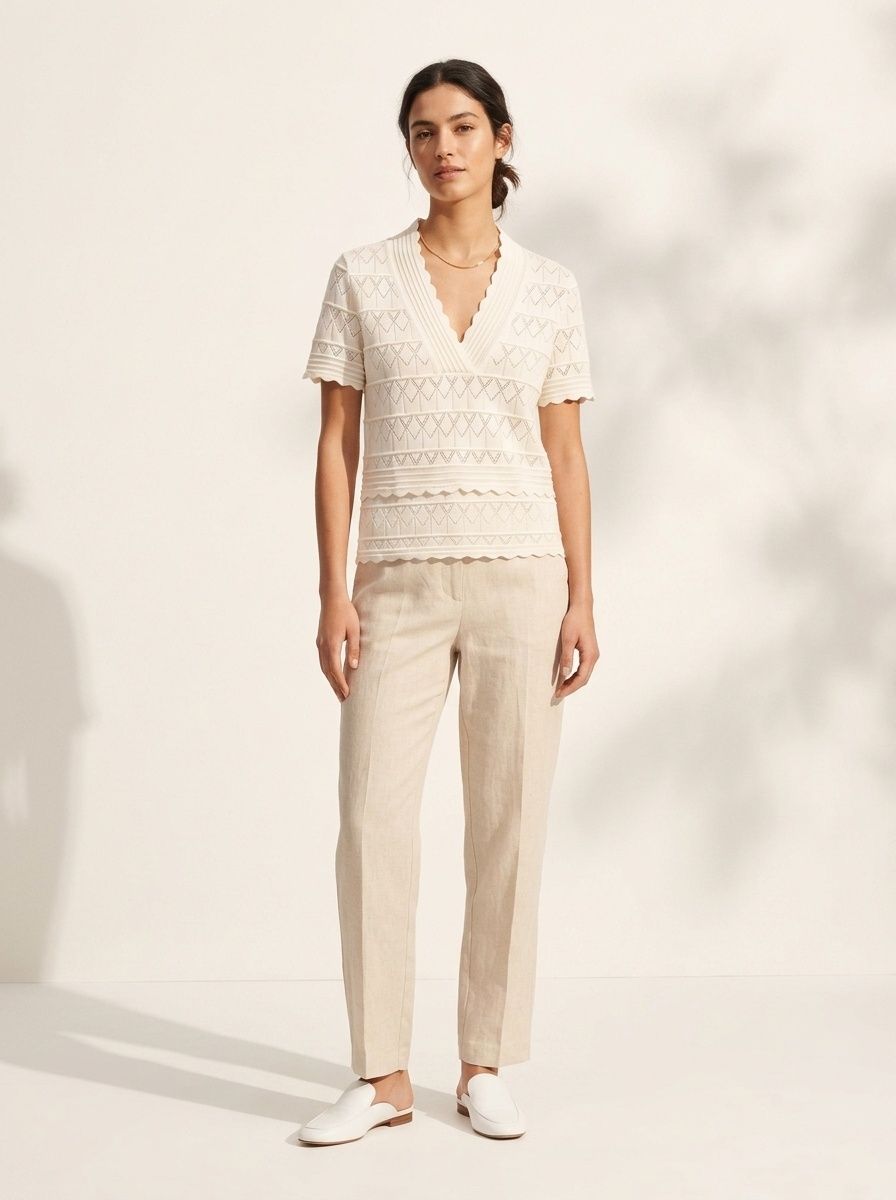 Elegante top a maniche corte con scollo a V e orlo smerlato, in maglia traforata.