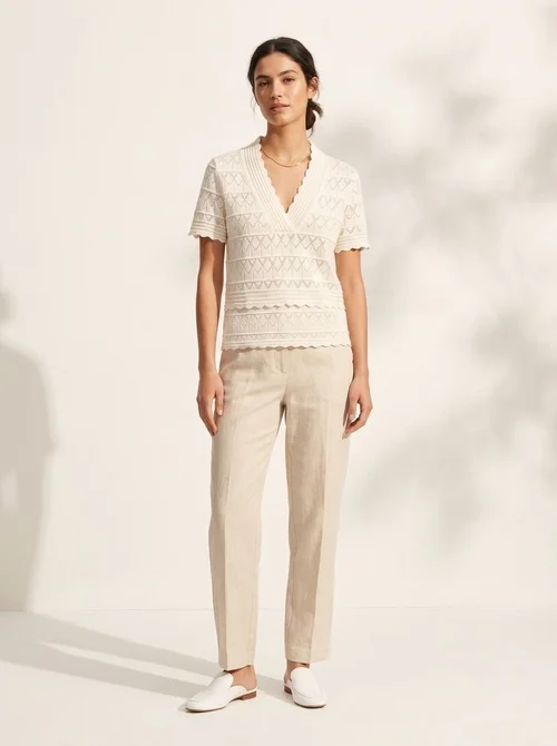 Elegante top a maniche corte con scollo a V e orlo smerlato, in maglia traforata.