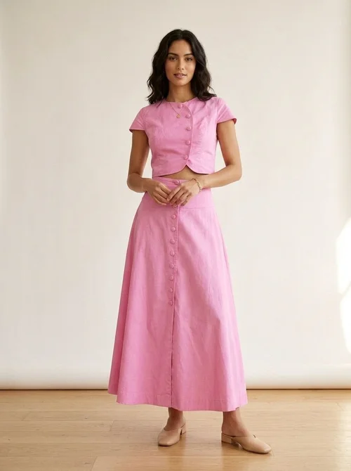 Completo rosa composto da crop top con bottoni sul davanti e gonna lunga.