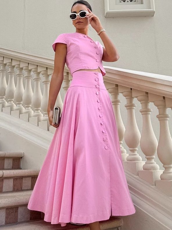 Conjunto rosa de dos piezas compuesto por top corto con botones delanteros y falda larga.
