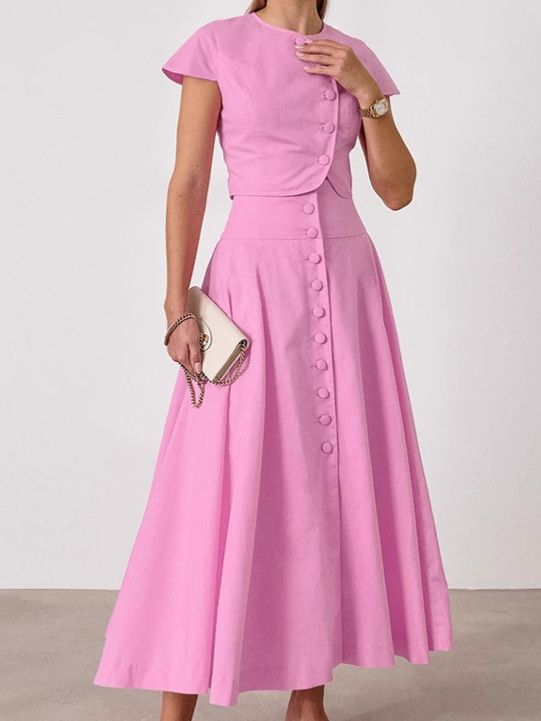 Conjunto rosa de dos piezas compuesto por top corto con botones delanteros y falda larga.