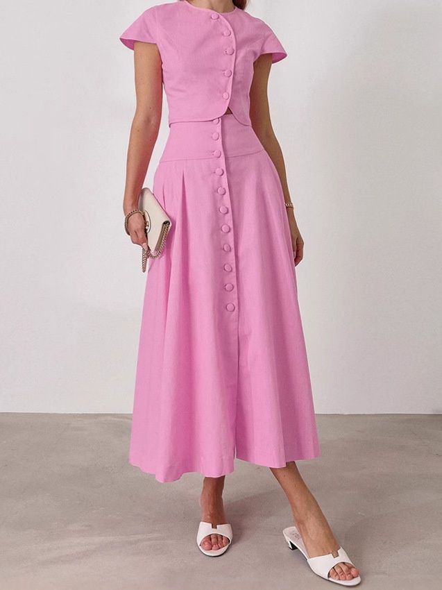 Conjunto rosa de dos piezas compuesto por top corto con botones delanteros y falda larga.