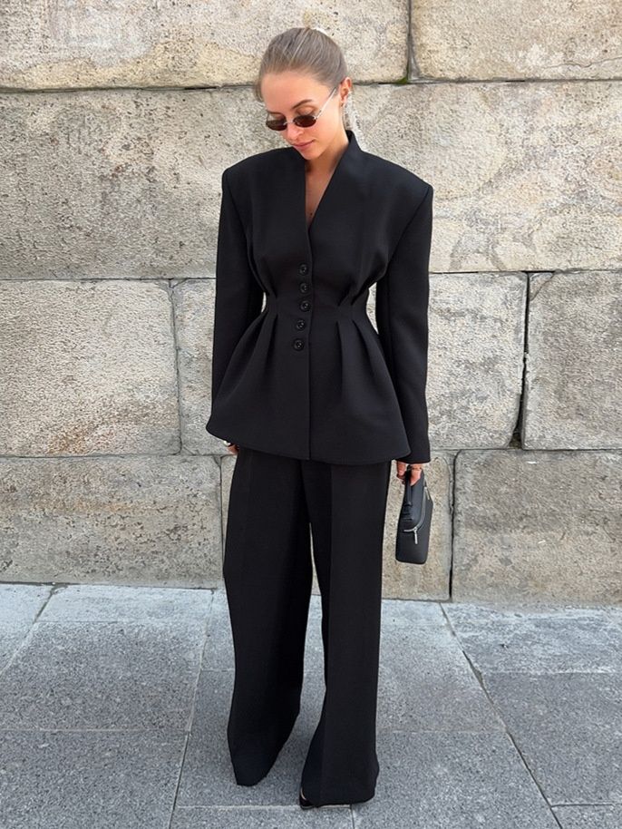 Elegante conjunto de chaqueta peplum negra y pantalón de pierna ancha.