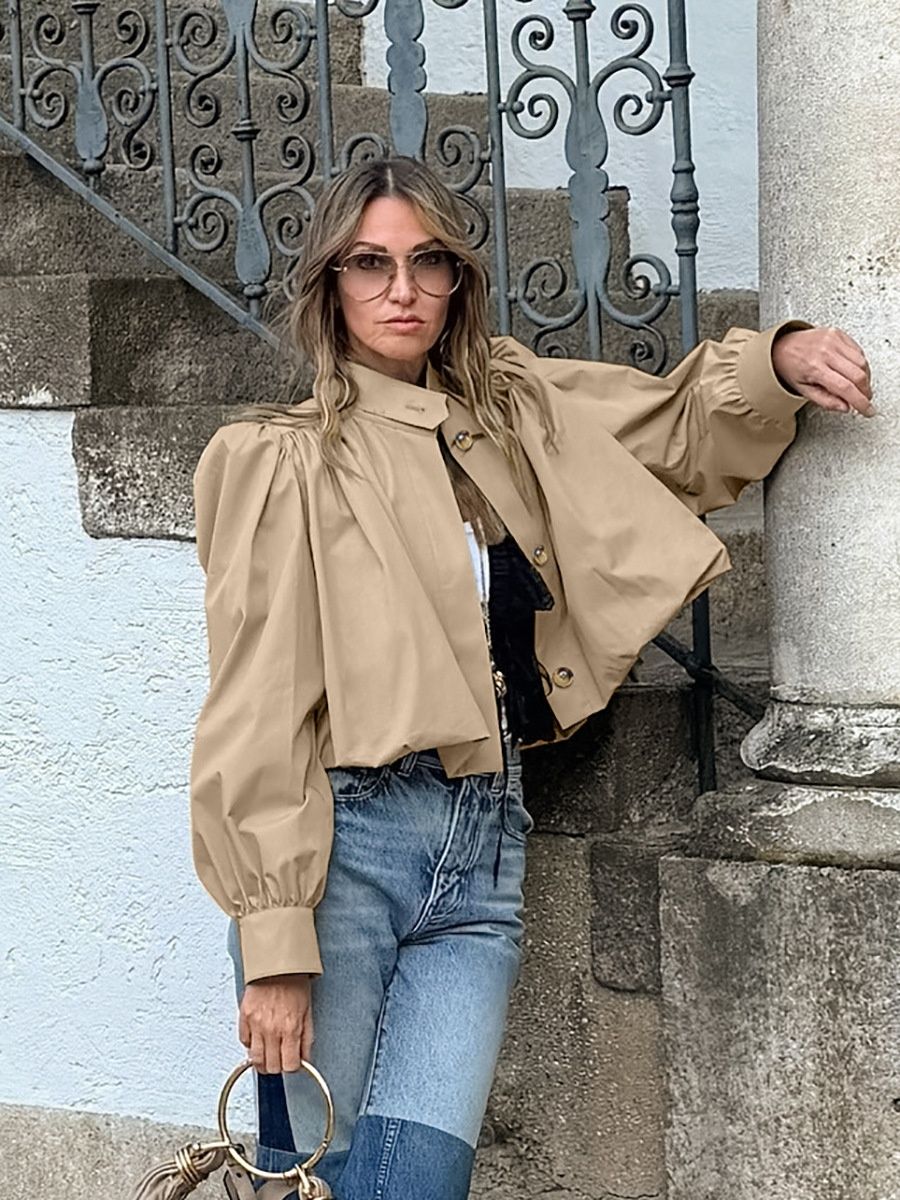 Blusa corta elegante de color beige con mangas abullonadas y cuello alto.