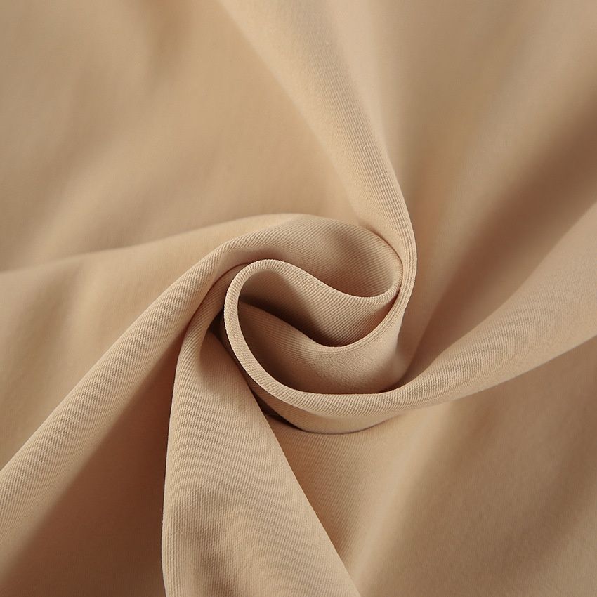 Blusa corta elegante de color beige con mangas abullonadas y cuello alto.