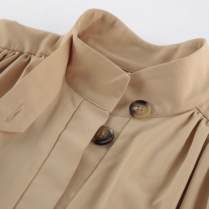 Blusa corta elegante de color beige con mangas abullonadas y cuello alto.