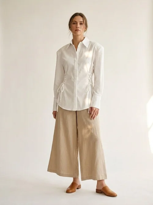 Elegante camicia bianca con spalline imbottite e allacciatura a bottoni