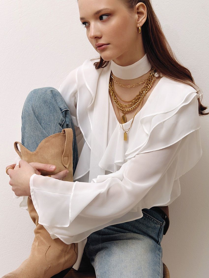 Blusa de gasa con volantes y lazo en el cuello.