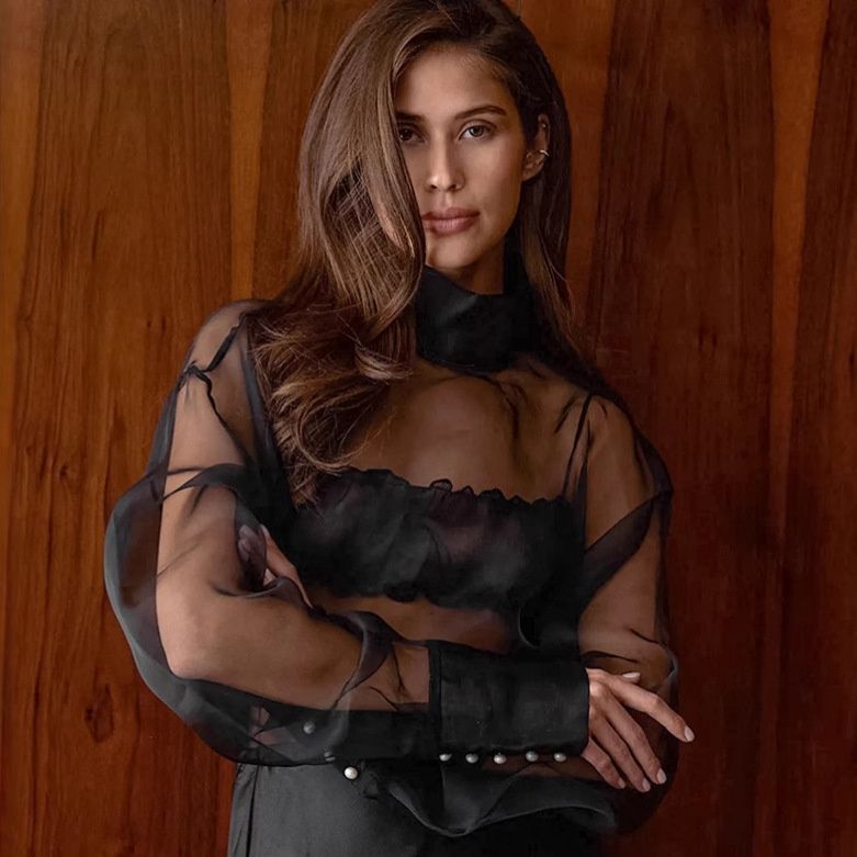 Blusa de organza transparente con cuello alto y mangas voluminosas.