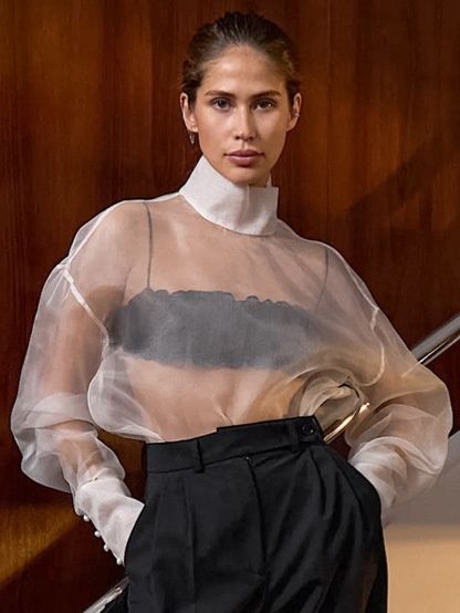 Blusa de organza transparente con cuello alto y mangas voluminosas.