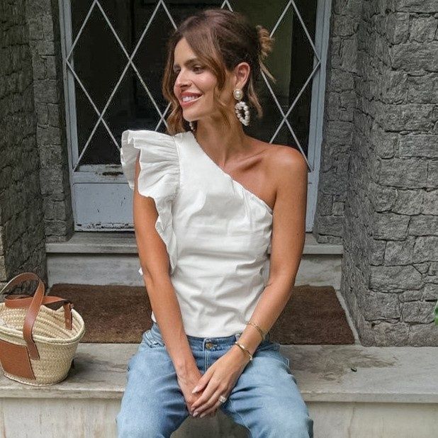 Elegante top blanco de un solo hombro con volantes.