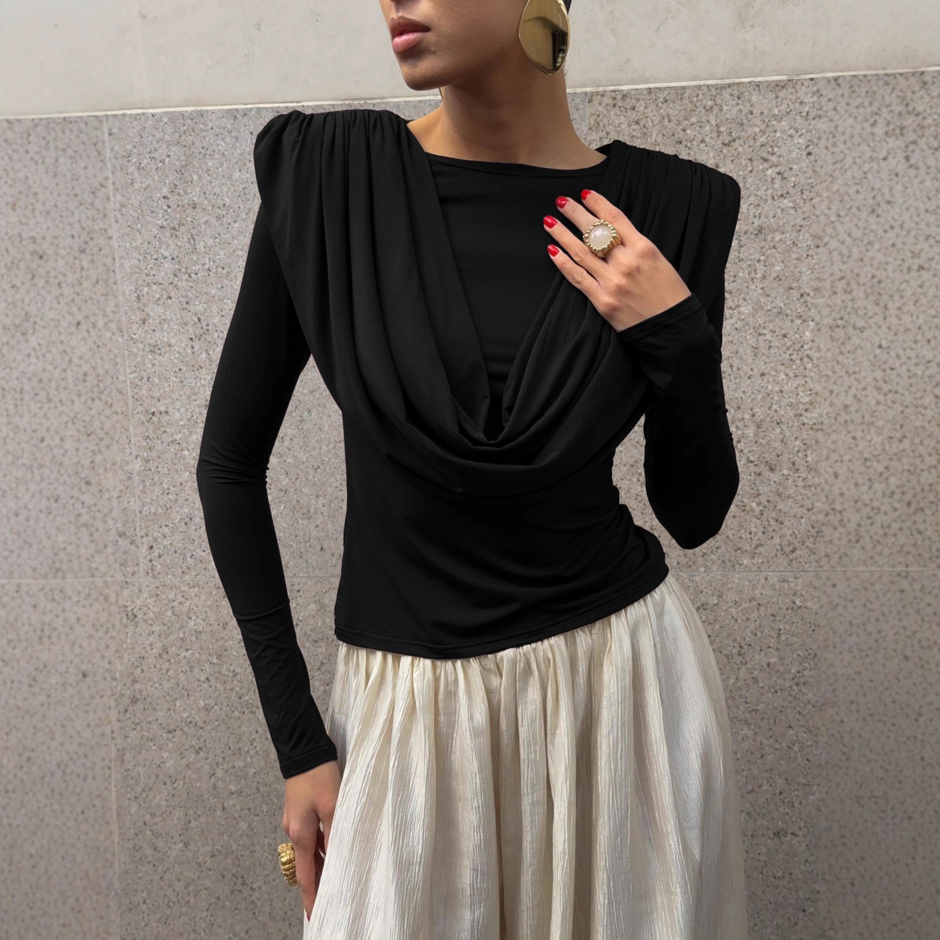 Elegante top de manga larga con cuello drapeado y hombreras acolchadas.