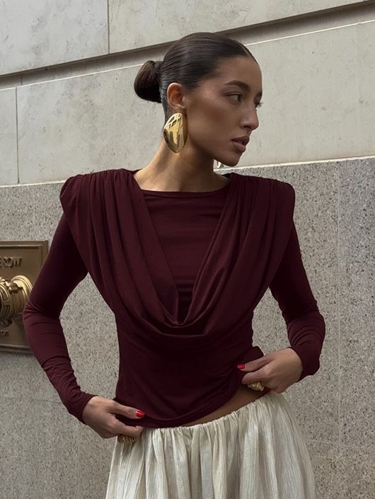 Elegante top de manga larga con cuello drapeado y hombreras acolchadas.