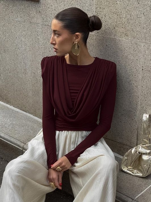 Elegante top de manga larga con cuello drapeado y hombreras acolchadas.