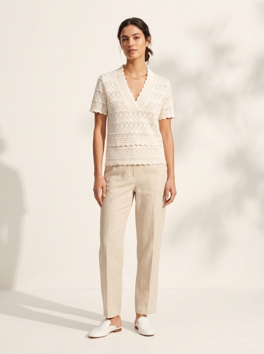 Elegante top a maniche corte con scollo a V e orlo smerlato, in maglia traforata.