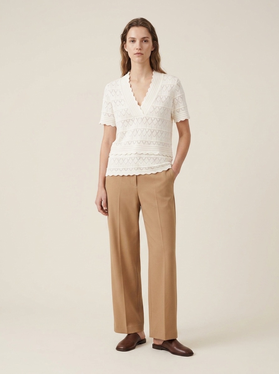 Elegante top a maniche corte con scollo a V e orlo smerlato, in maglia traforata.