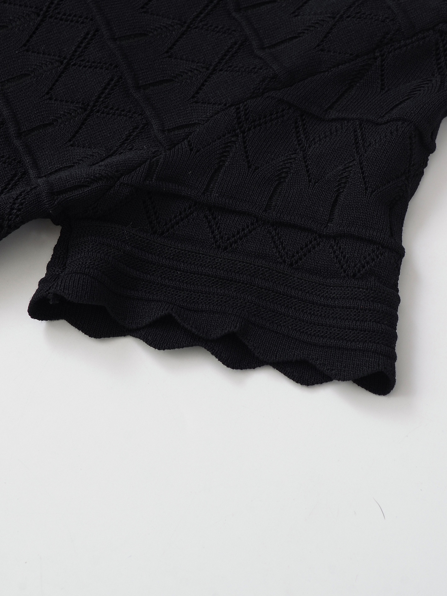 Elegante top a maniche corte con scollo a V e orlo smerlato, in maglia traforata.