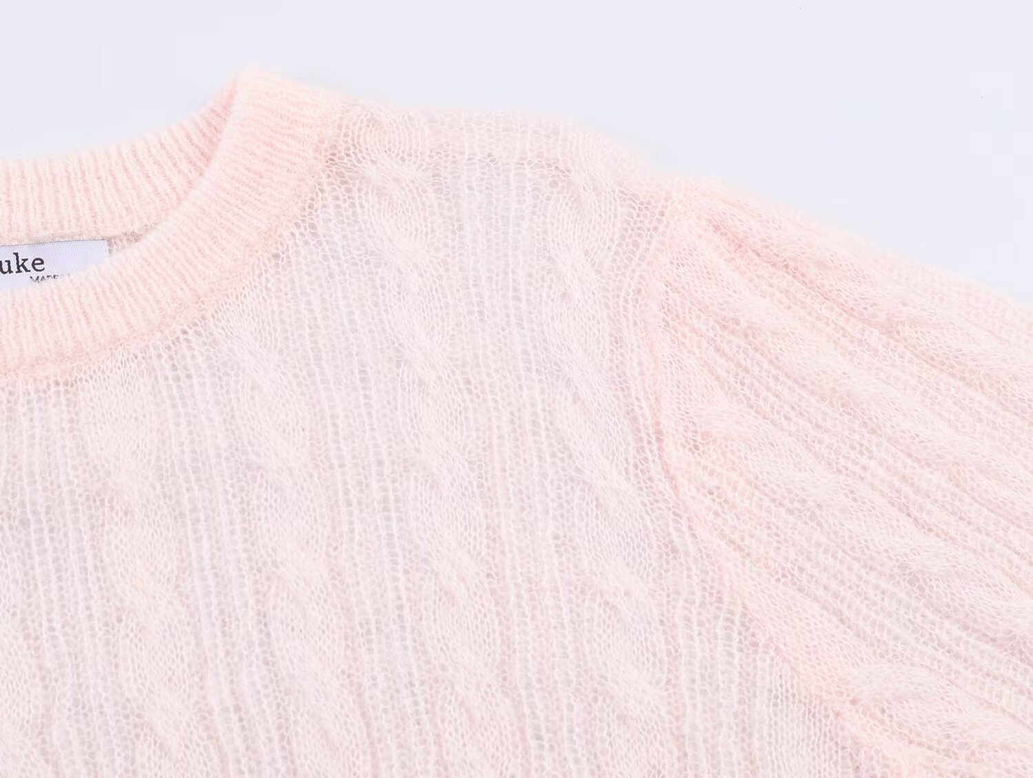 Elegante top rosa chiaro in maglia a trecce con maniche a sbuffo trasparenti.