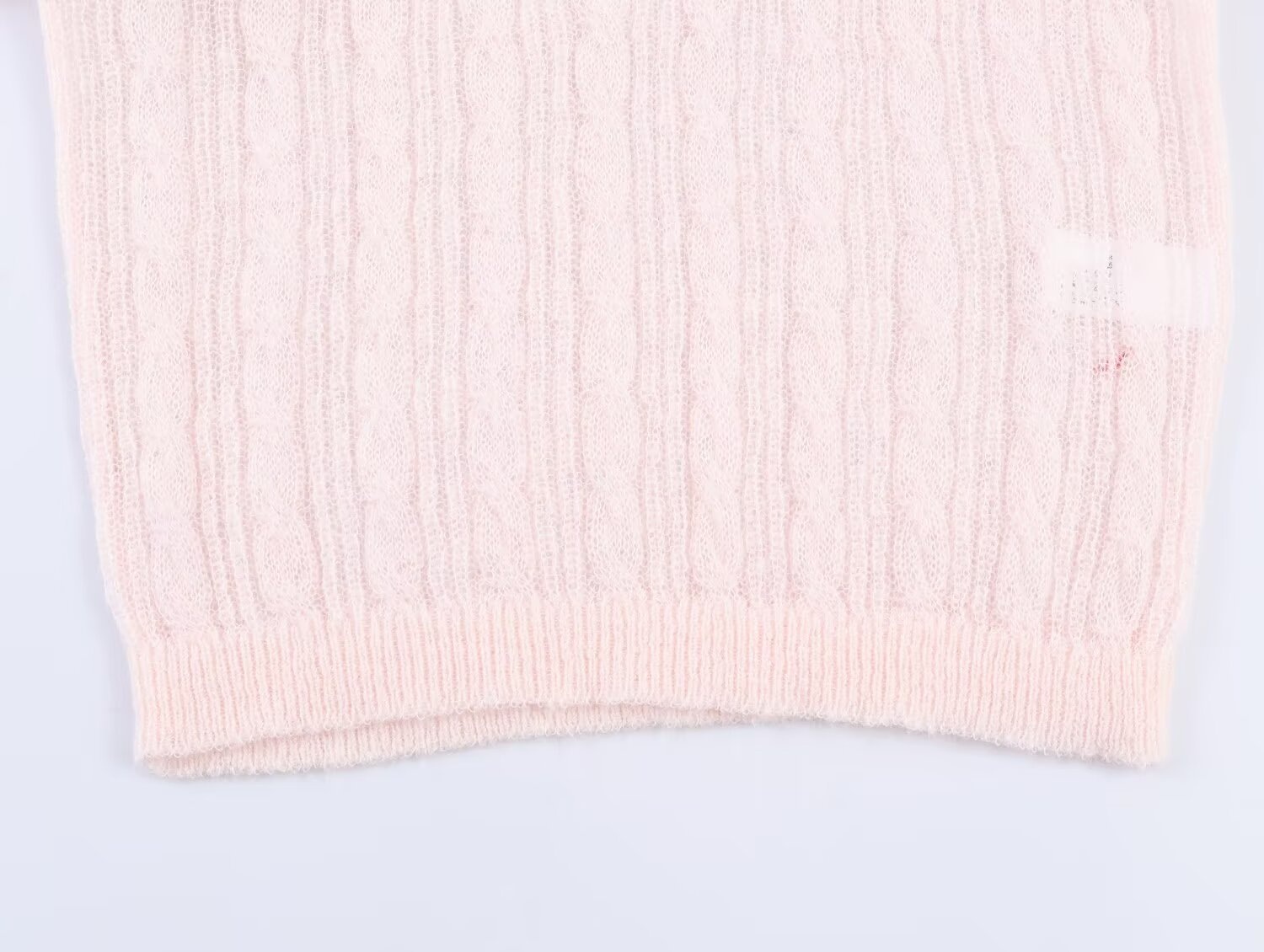 Elegante top rosa chiaro in maglia a trecce con maniche a sbuffo trasparenti.