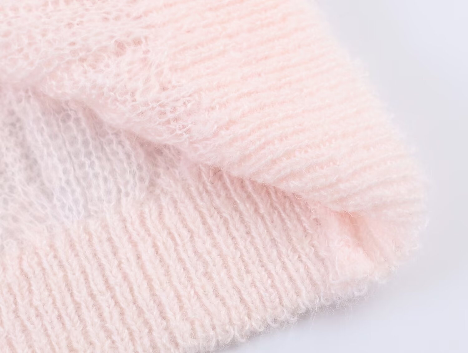 Elegante top rosa chiaro in maglia a trecce con maniche a sbuffo trasparenti.