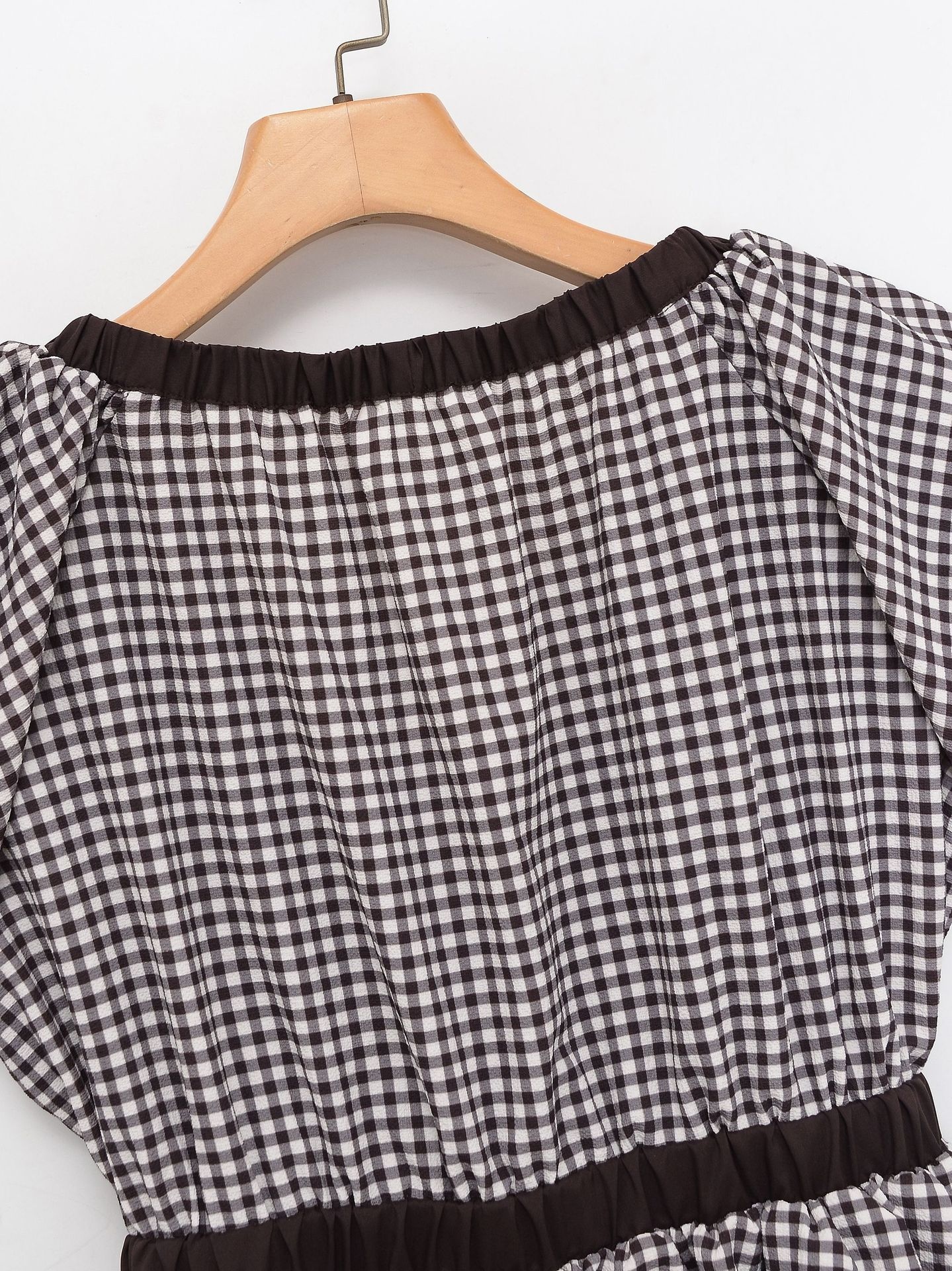 Elegante camicetta peplum a quadretti vichy con fiocco e maniche a sbuffo.