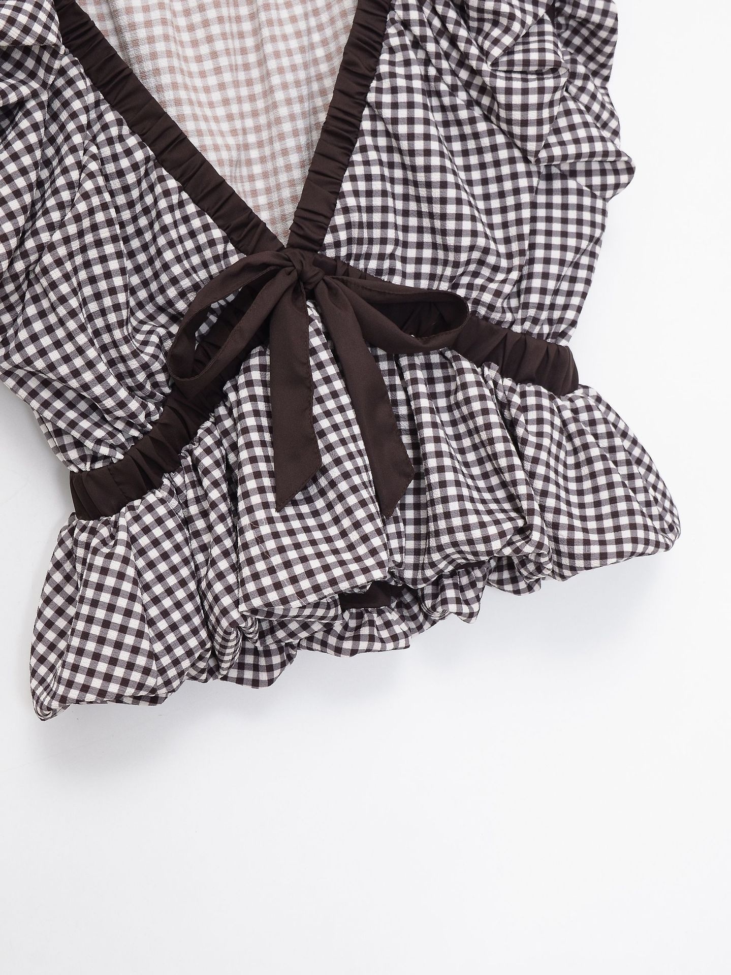 Elegante camicetta peplum a quadretti vichy con fiocco e maniche a sbuffo.