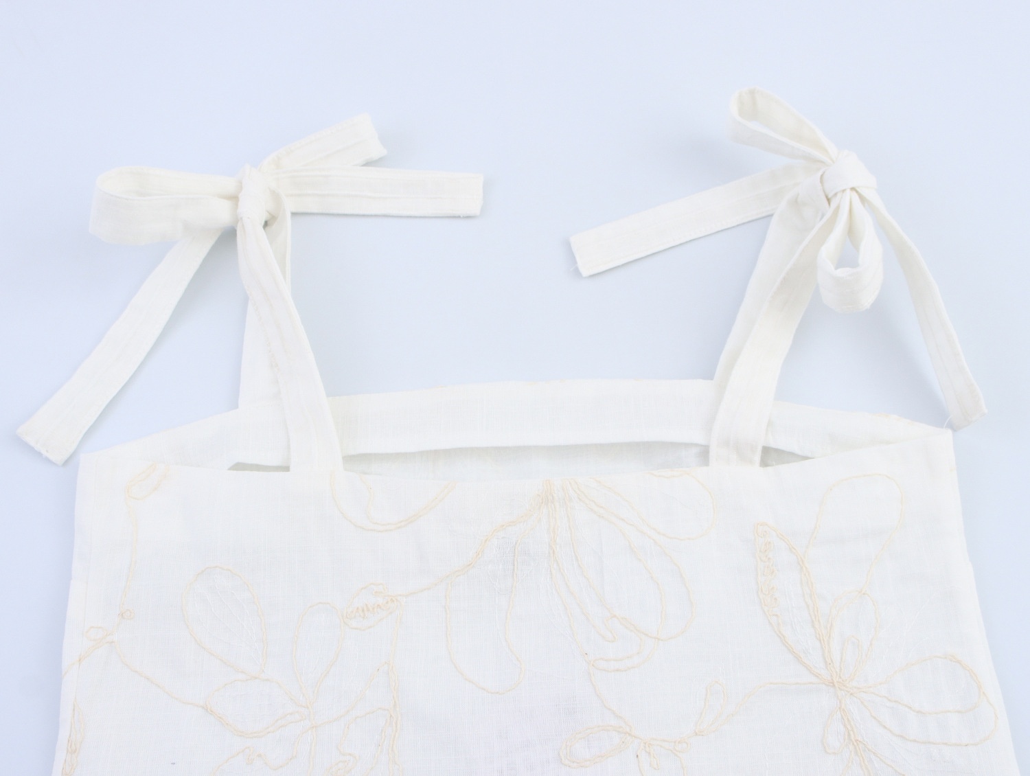 Top a canotta bianco con stampa floreale e laccetti sulle spalle.