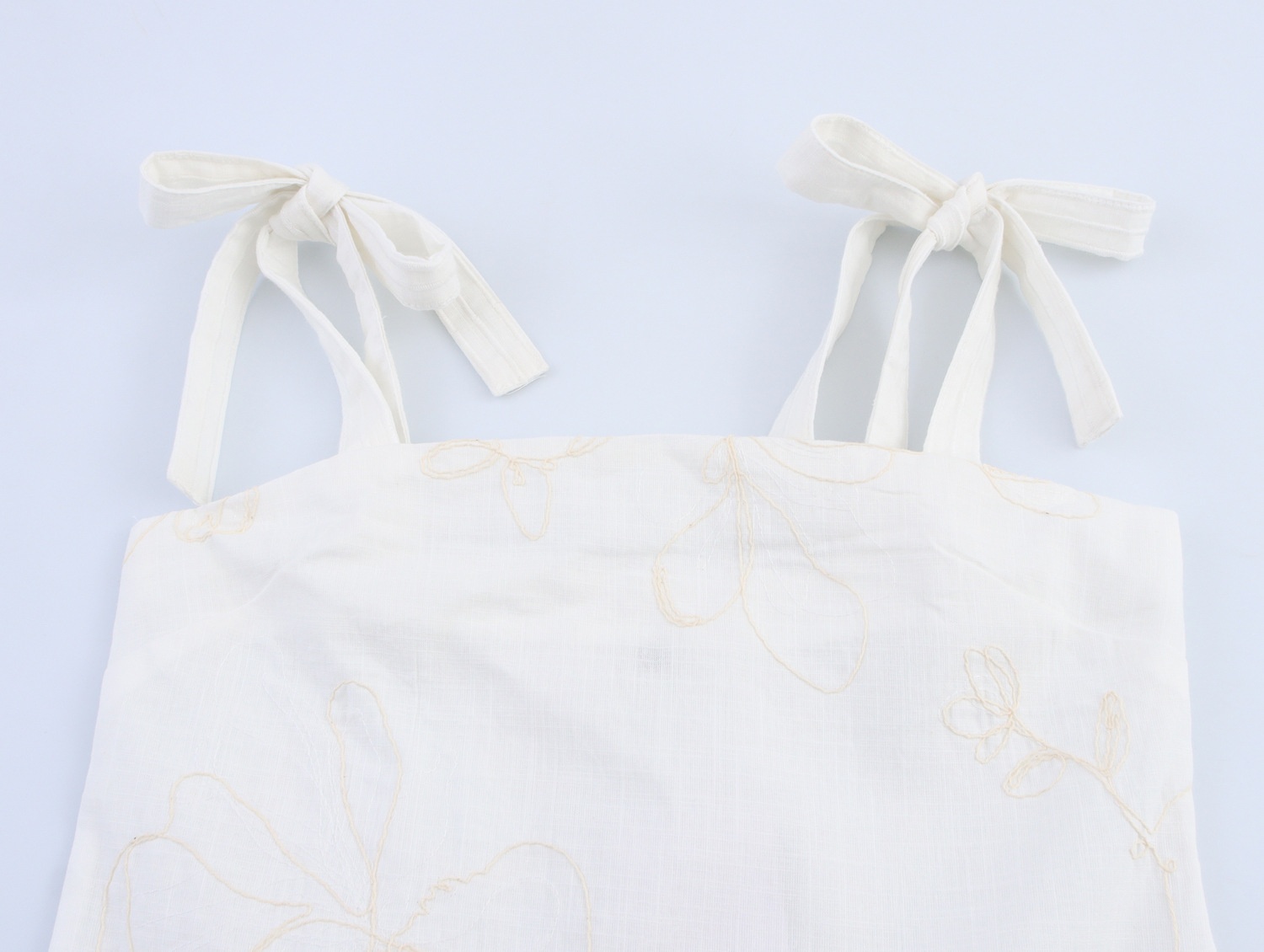 Top a canotta bianco con stampa floreale e laccetti sulle spalle.
