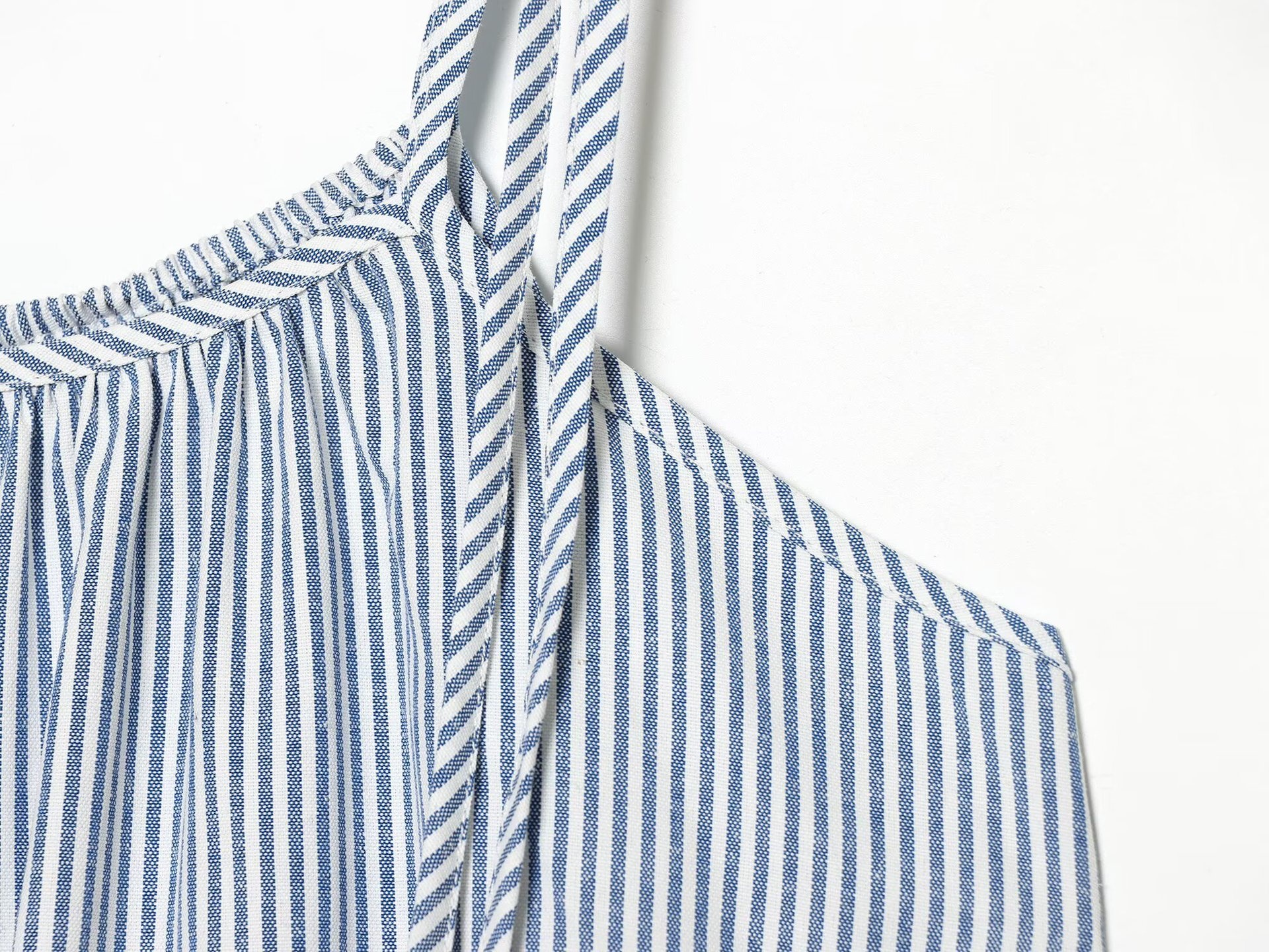 Elegante top a canotta con volant a righe blu e bianche e laccetti sulle spalle.