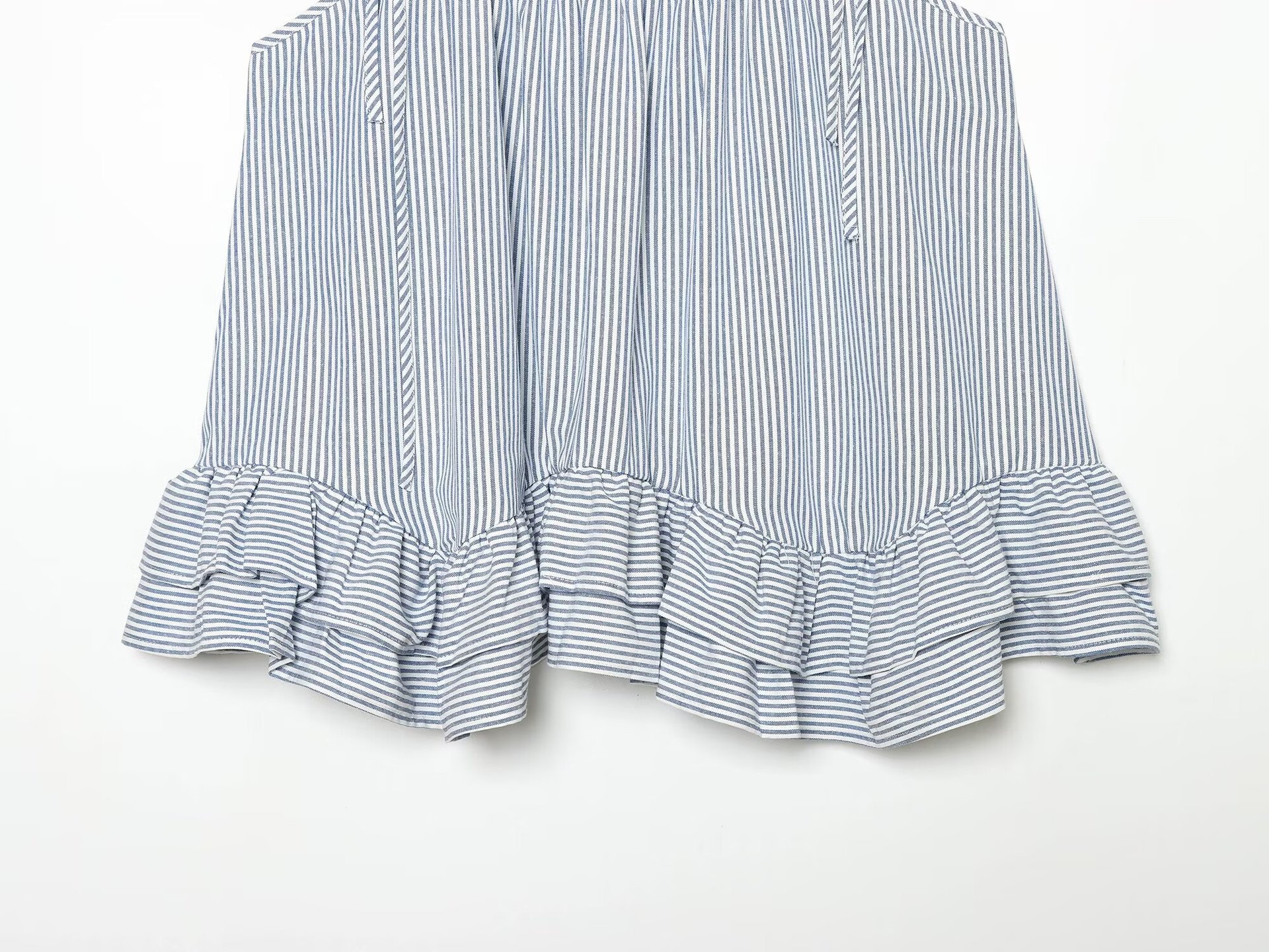 Elegante top a canotta con volant a righe blu e bianche e laccetti sulle spalle.