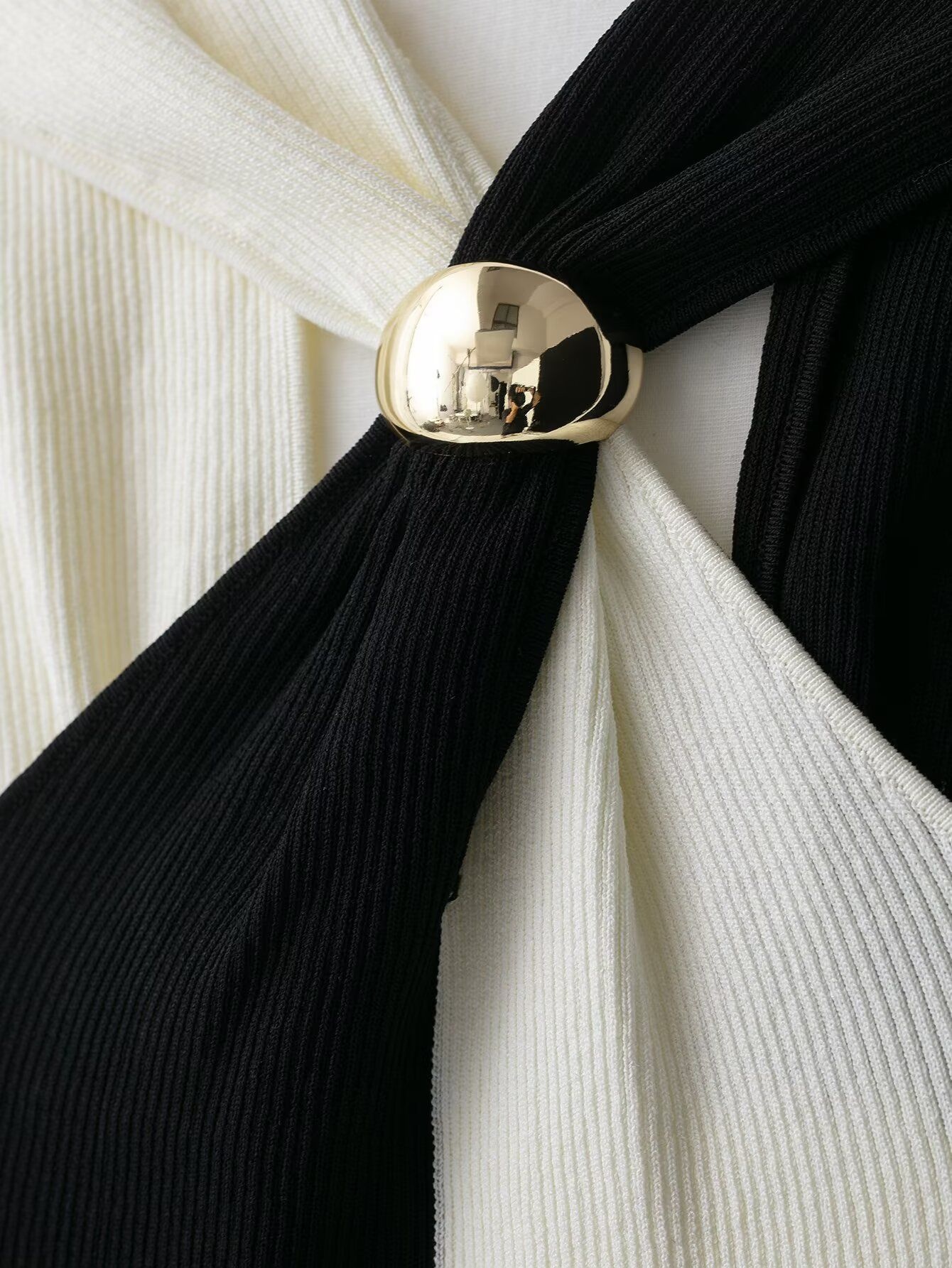 Elegante top a collo alto a coste con blocchi di colore e dettaglio ad anello in metallo.