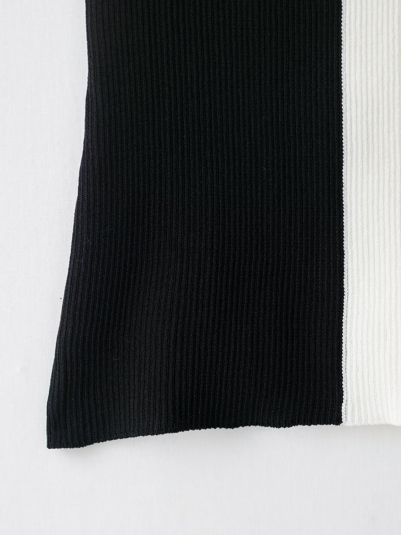 Elegante top a collo alto a coste con blocchi di colore e dettaglio ad anello in metallo.