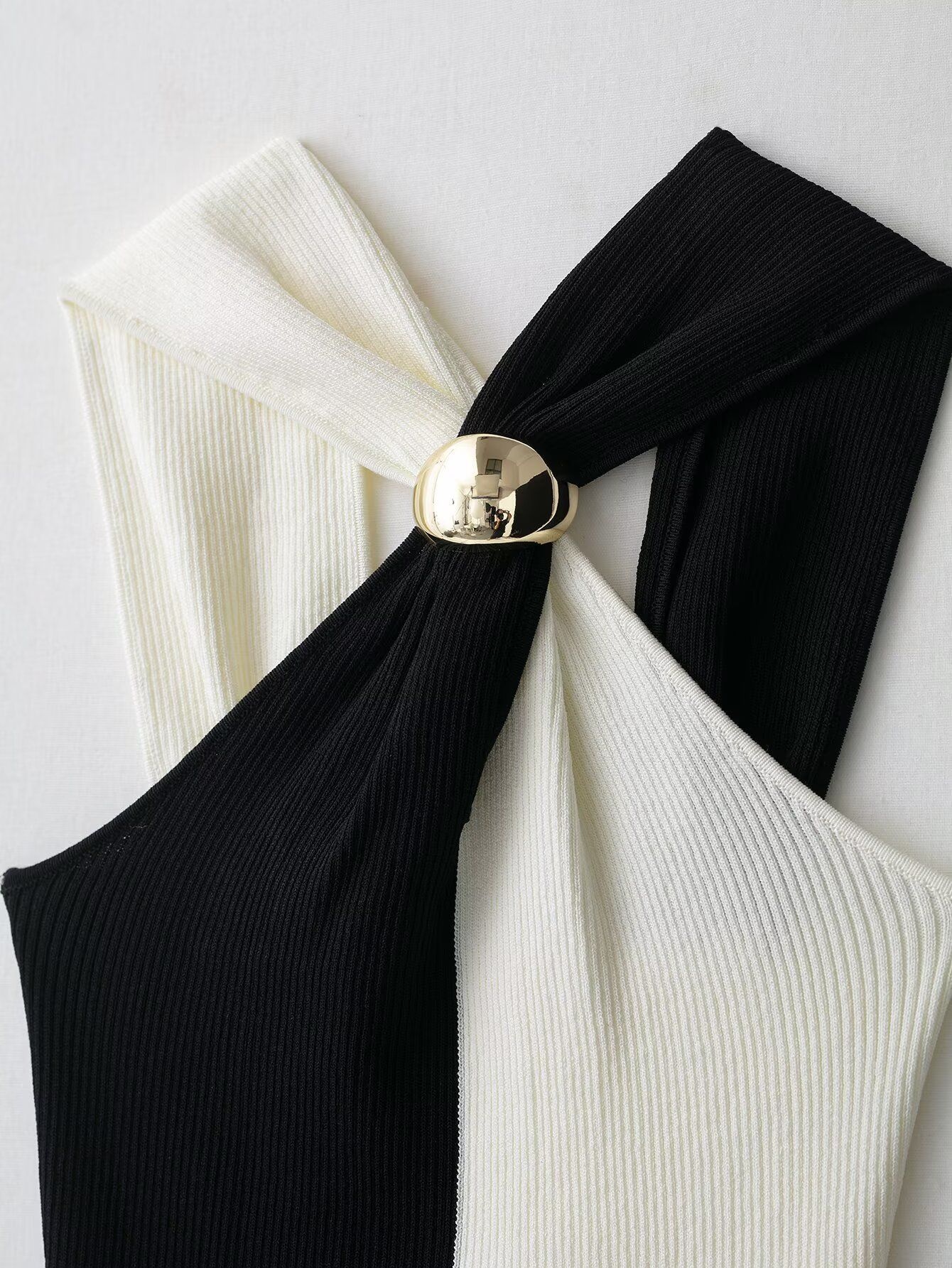 Elegante top a collo alto a coste con blocchi di colore e dettaglio ad anello in metallo.