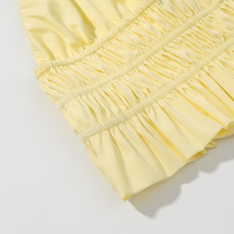 Elegante crop top giallo con scollo all'americana, orlo arricciato e volant.