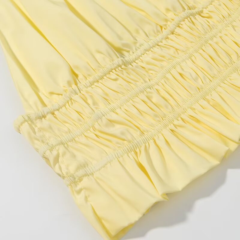 Elegante crop top giallo con scollo all'americana, orlo arricciato e volant.