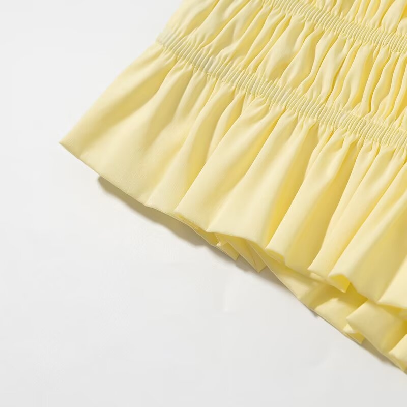 Elegante crop top giallo con scollo all'americana, orlo arricciato e volant.