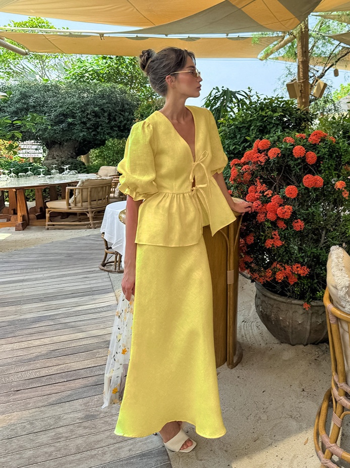 Completo giallo composto da top peplum con maniche a sbuffo e gonna lunga.