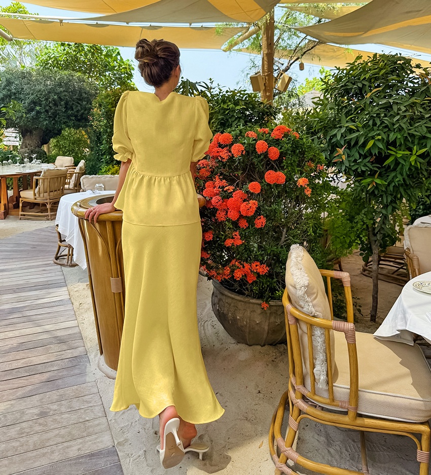 Completo giallo composto da top peplum con maniche a sbuffo e gonna lunga.