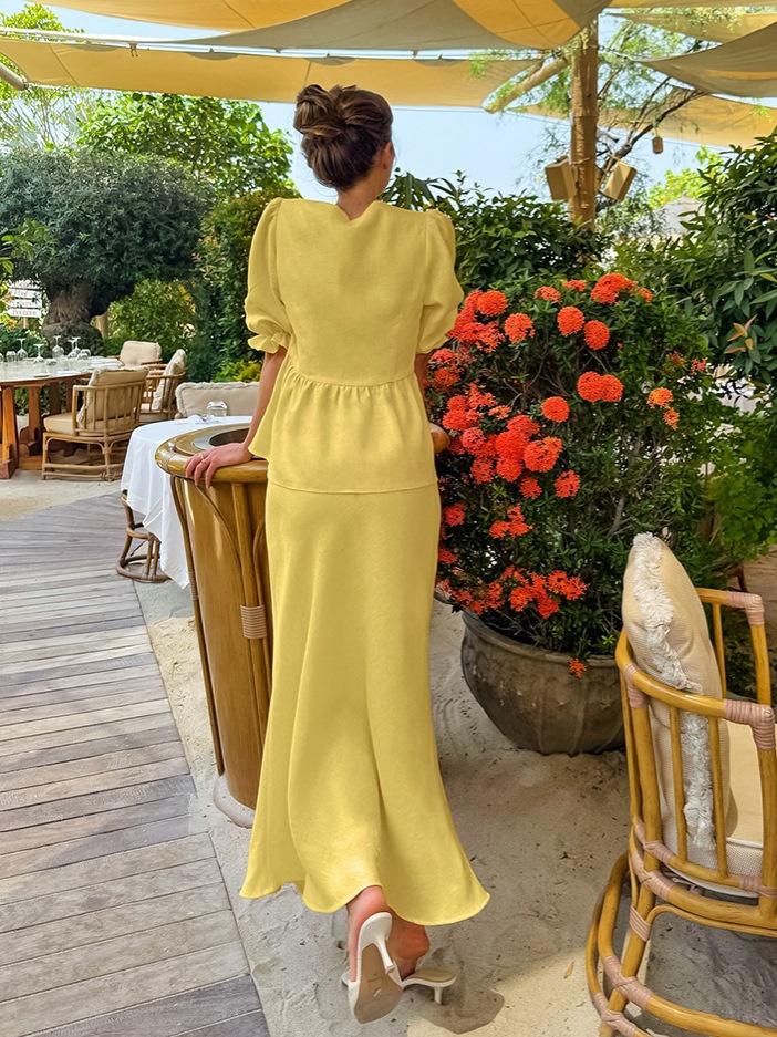 Completo giallo composto da top peplum con maniche a sbuffo e gonna lunga.